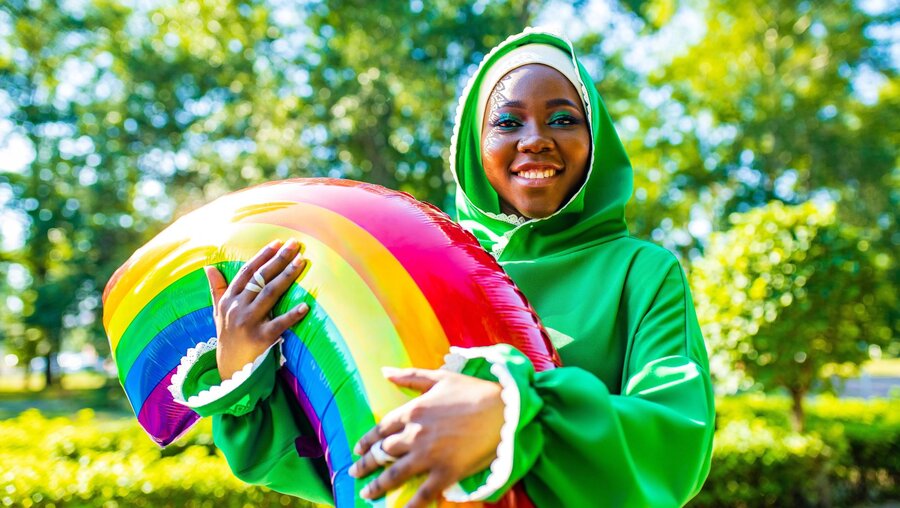Symbolbild Eine Frau mit Kopftuch und einem Ballon in Regenbogenfarben / © yurakrasil (shutterstock)