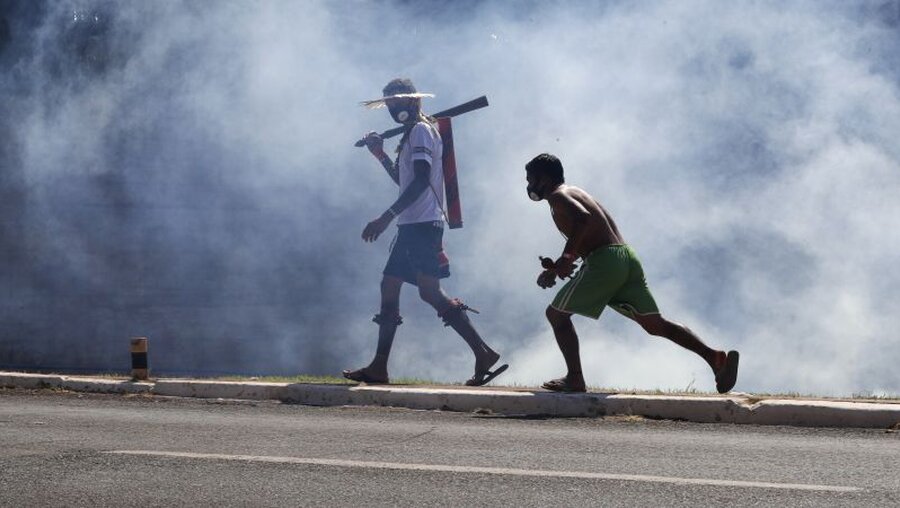Indigene gehen durch Rauch von Tränengas bei einer Demonstration in Brasilia / © Eraldo Peres/AP (dpa)