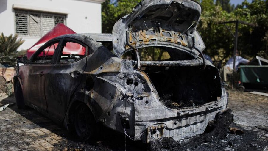 Israel, Lod: Ein ausgebranntes Auto steht vor einem beschädigten Wohnhaus / © Ilia Yefimovich (dpa)