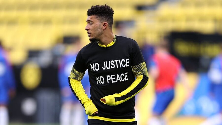 Jadon Sancho von Borussia Dortmund trägt beim Aufwärmen ein T-Shirt mit der Aufschrift "No Justice No Peace" / © Lars Baron (dpa)