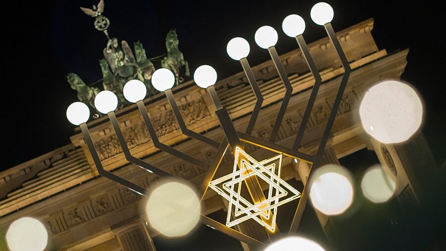 Lichter eines Chanukka-Leuchters vor dem Brandenburger Tor / ©  Paul Zinken (dpa)