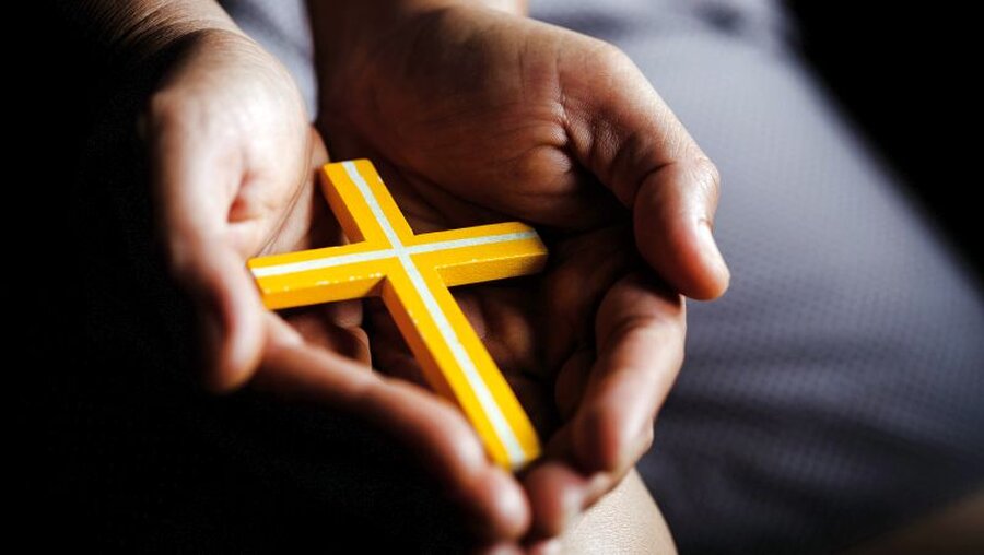 Jugendlicher mit einem Kreuz in der Hand / © Doidam 10 (shutterstock)