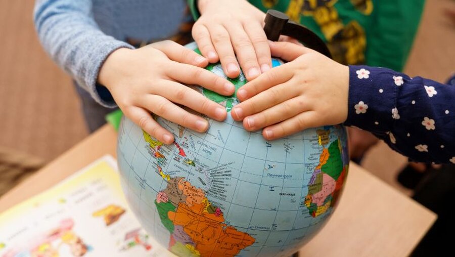 Kinder halten Hände auf Globus / © Spring Melody (shutterstock)