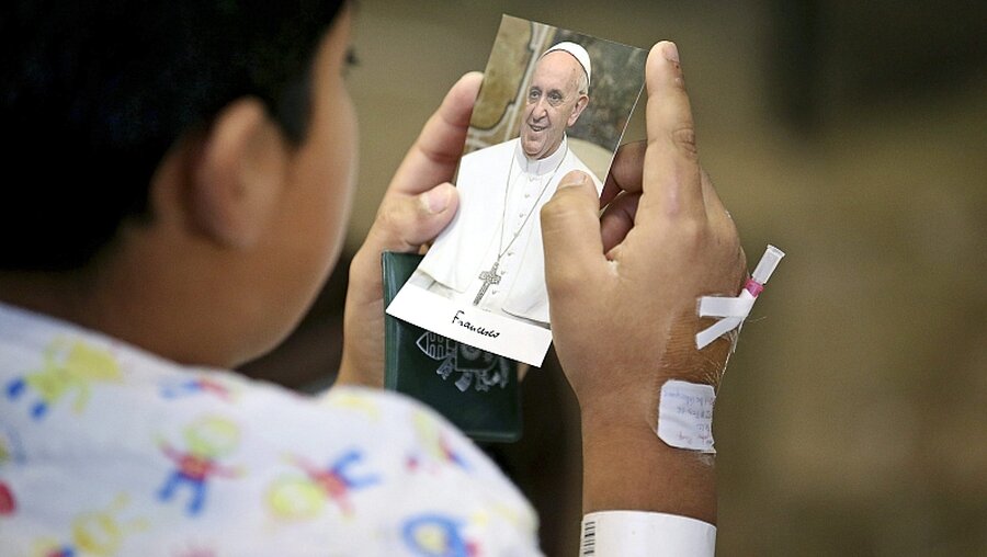 Kind in einem Krankenhaus mit einem Bild von Papst Franziskus / © Alessandro Di Meo (dpa)