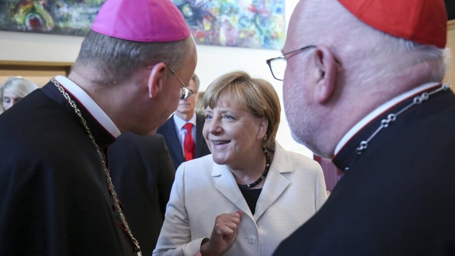 Kirche trifft Politk: Die Bischöfe Franz-Josef Overbeck (l.) und Reinhard Kardinal Marx (r.) mit Kanzlerin Angela Merkel / © Markus Nowak (KNA)
