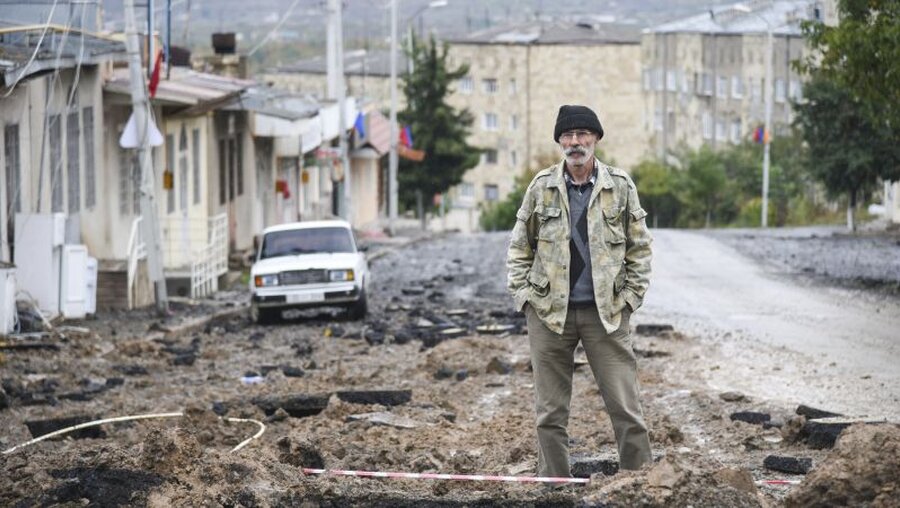 Konflikt in Berg-Karabach: Ein Mann steht auf einer beschädigten Straße / © David Ghahramanyan/NKR InfoCenter PAN Photo/AP (dpa)