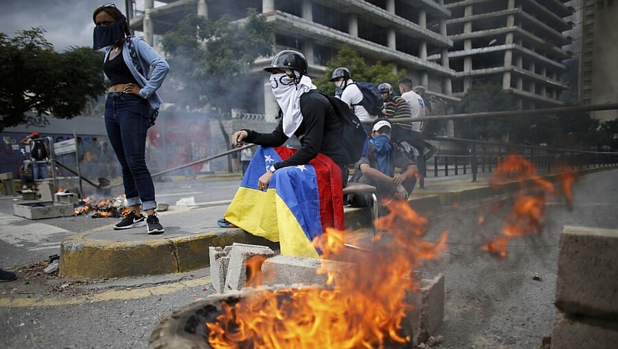 Demonstranten blockieren eine Straße in Venezuelas Hauptstadt Caracas / © Ariana Cubillos (dpa)