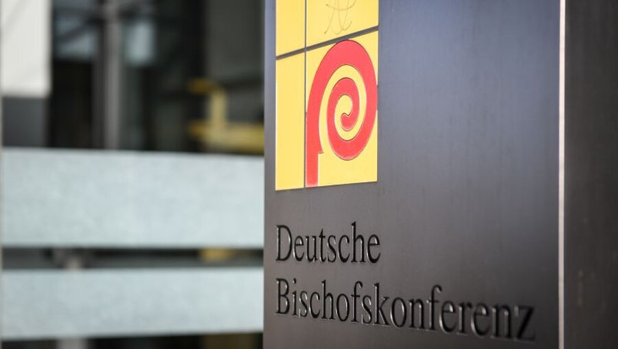 Logo der Deutschen Bischofskonferenz (DBK) auf einem Schild neben dem Eingang zum Sekretariat der DBK / © Julia Steinbrecht (KNA)