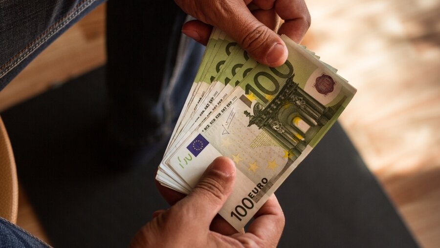 Mann hält Geldscheine in der Hand / © Kseniia Zagrebaeva (shutterstock)