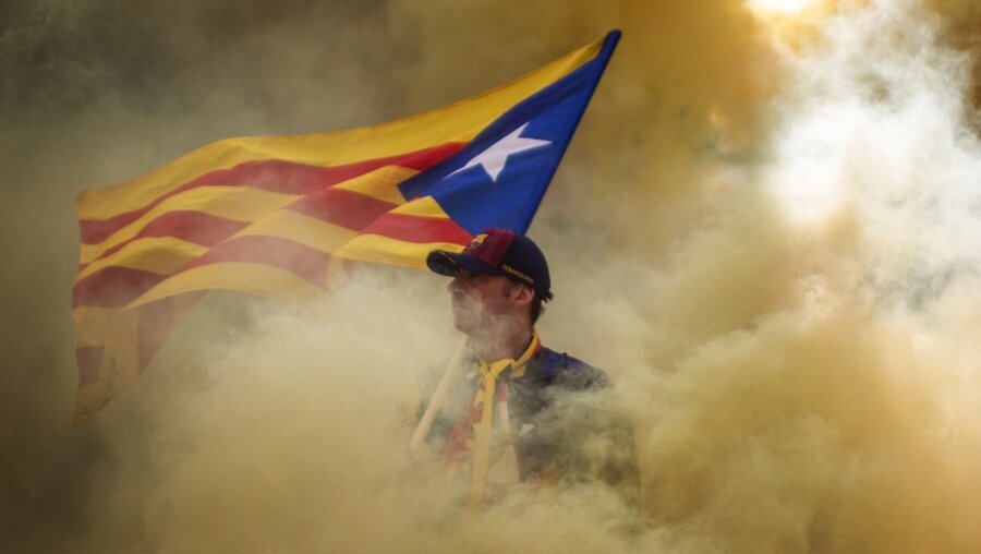 Mann mit katalanischer Unabhängigkeitsfahne steht im Rauch / © Emilio Morenatti (dpa)