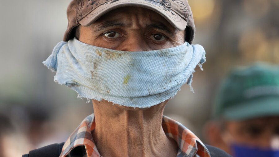 Ein Mann trägt ein Stück Stoff als Gesichtsmaske  / © Ariana Cubillos (dpa)