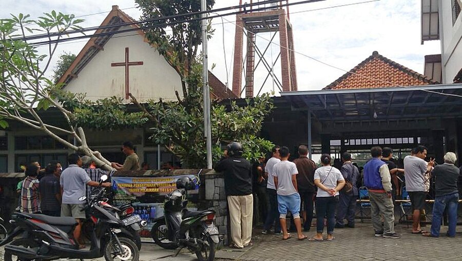 Menschen stehen nach einem Schwertangriff vor einer indonesischer Kirche / © Slamet Riyadi (dpa)