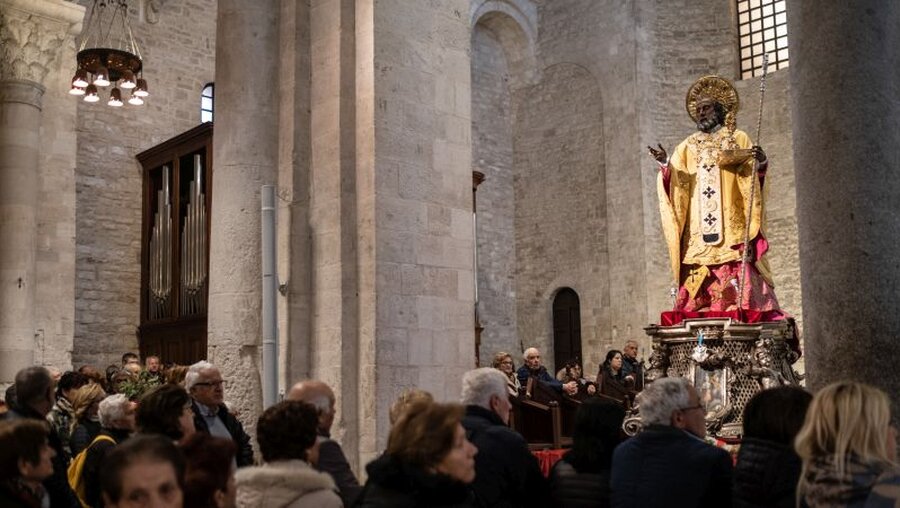 Menschen stehen vor einer Figur des heiligen Nikolaus in der Basilika San Nicola (Archiv) / © Francesco Pistilli (KNA)