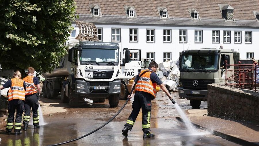 Nach dem Hochwasser in Nordrhein-Westfalen: Die Feuerwehr befreit eine Straße vom Schlamm / © Oliver Berg (dpa)