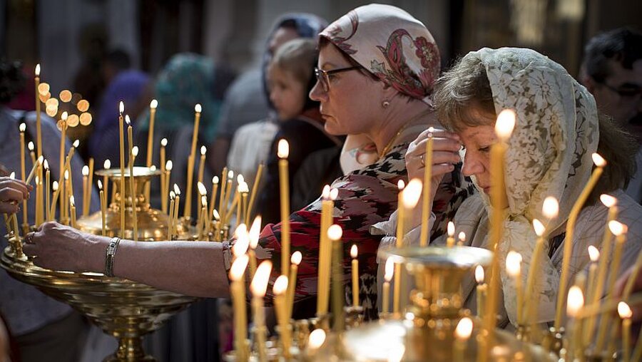 Orthodoxe Christen zünden eine Kerze im Rahmen der Ostermesse in Litauen an / © Mindaugas Kulbis (dpa)