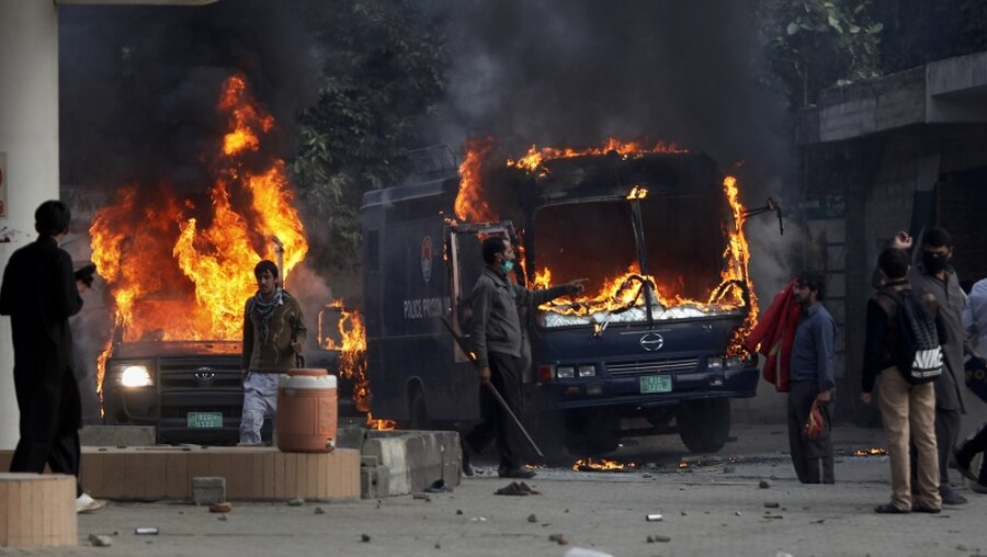Pakistanische Demonstranten in Islamabad neben brennenden Polizeiwagen / © Anjum Naveed (dpa)