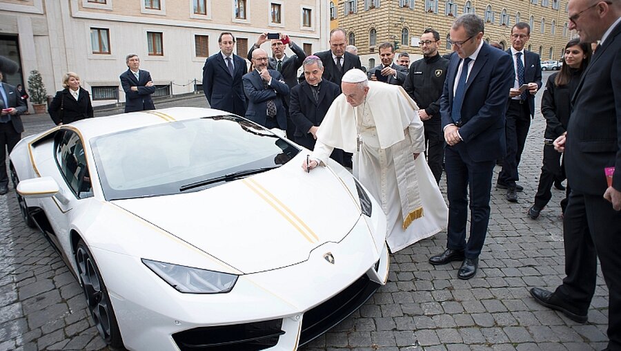 Papst Franziskus signiert den Lamborghini, den er geschenkt bekommen hat. Er lässt ihn für einen guten Zweck versteigern. / © Osservatore Romano (KNA)
