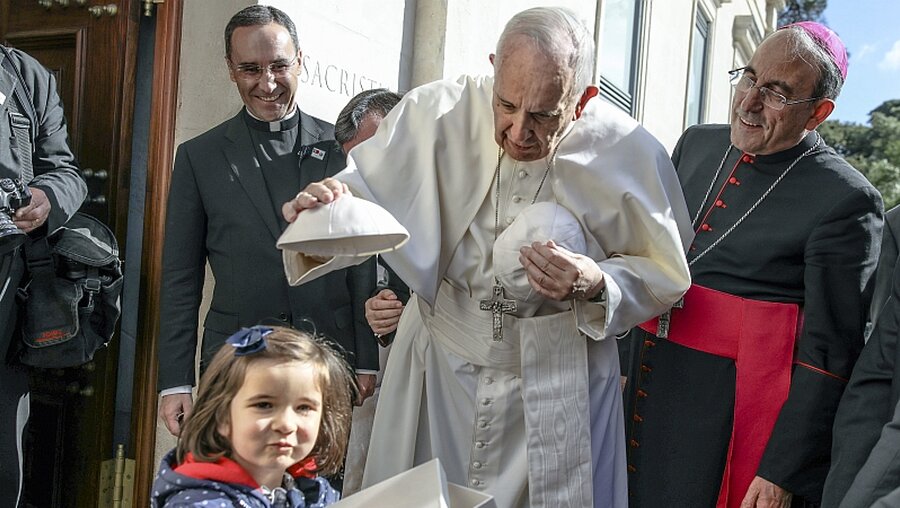 Papst Franziskus (2.v.r.) tauscht in Fatima seinen Pileolus mit dem eines Kindes. / © Paulo Cunha (dpa)