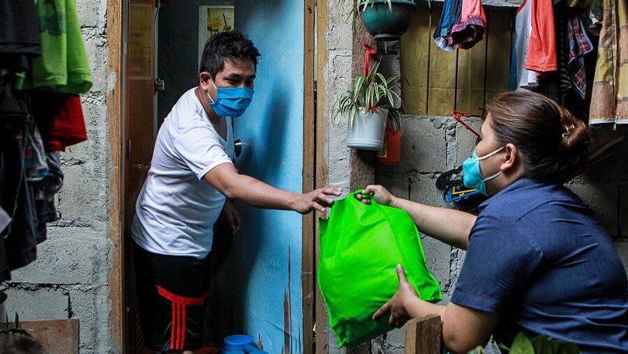 Philippinen: Ein Anwohner eines Slums erhält eine Tasche mit Hilfsmitteln (Archivbild) / © Rouelle Umali (dpa)