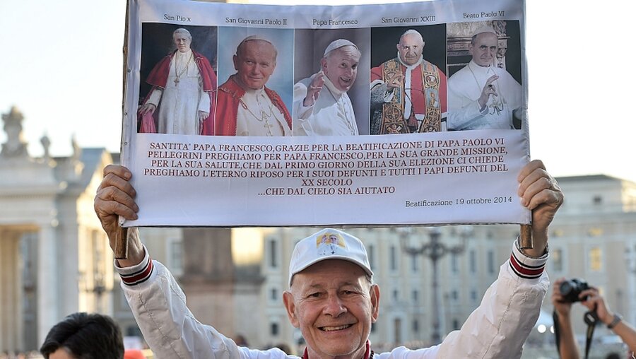 Plakat: Neben den Heiligen Pius X., Johannes Paul II. und Johannes XXIII., sind auch der aktuelle Papst Franziskus und Papst Paul VI. abgebildet / © Cristian Gennari (KNA)