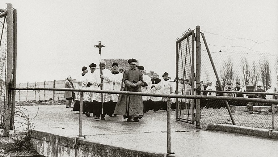 Polnische Geistliche ziehen in Gedenken an die Befreiung des Konzentrationslagers Dachau durch das Lagertor. / © KNA-Bild (KNA)