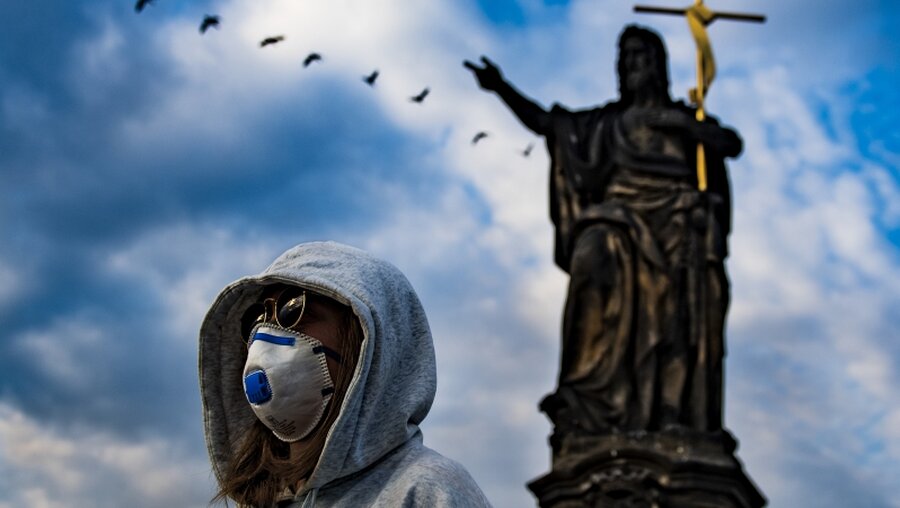 Prag: Eine Frau mit Mundschutz steht auf der Karlsbrücke / © Roman Vondrou (dpa)
