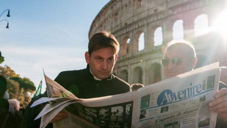 Priester und Laie lesen vor dem Kolosseum in einer Zeitung / © davide bonaldo (shutterstock)