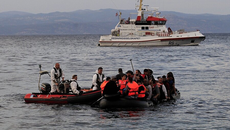 Frontex-Mitarbeiter mit Flüchtlingen / © Orestis Panagiotou (dpa)
