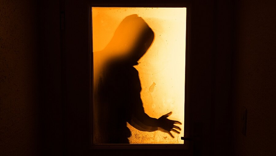 Schatten eines Mannes hinter Wohnungstür / © Nicolas Armer (dpa)