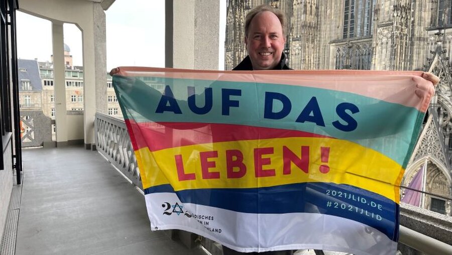 Stadtdechant Robert Kleine mit Flagge vor dem Kölner Dom (Katholisches Stadtdekanat Köln)
