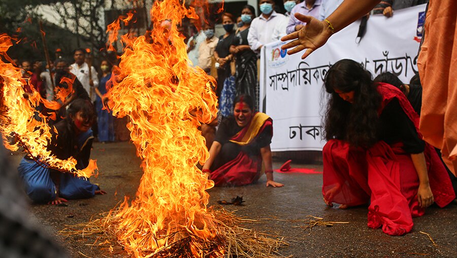 Studenten knien während einer Demonstration um ein Feuer / © Nayem Shaan (dpa)