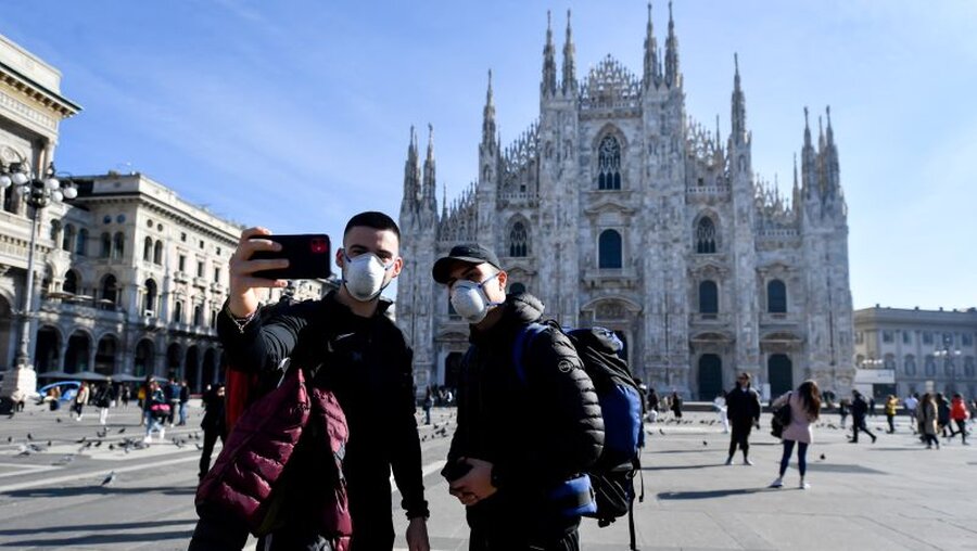  Touristen fotografieren sich mit Mundschutz vor der Kathedrale in Mailand / © Claudio Furlan (dpa)