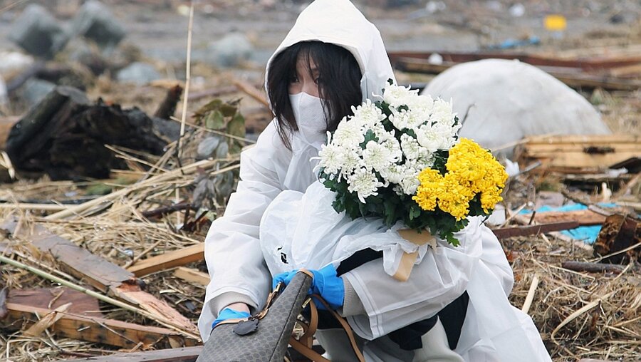 Trauer in Fukushima: Eine Frau betet und legt Blumen am Unglücksort nieder   / © Koichi Kamoshida (dpa)