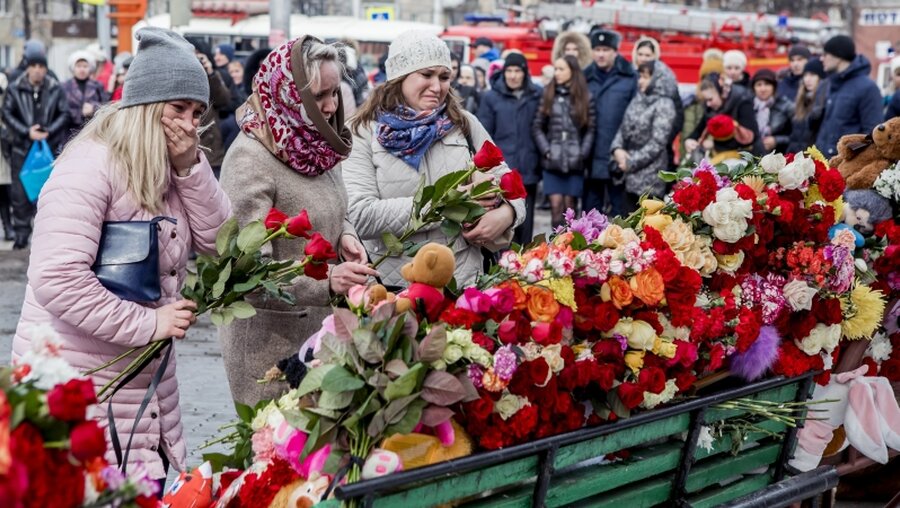 Trauernde legen Blumen nieder nach einem Brand eines Einkaufszentrum / © Uncredited/AP (dpa)