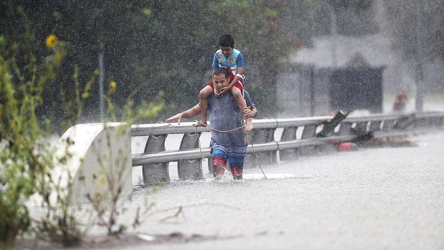 Ein Mann watet am mit seinem Sohn durch kniehohes Wasser in Houston  / © Marie D. De Jesus/Houston Chronicle (dpa)