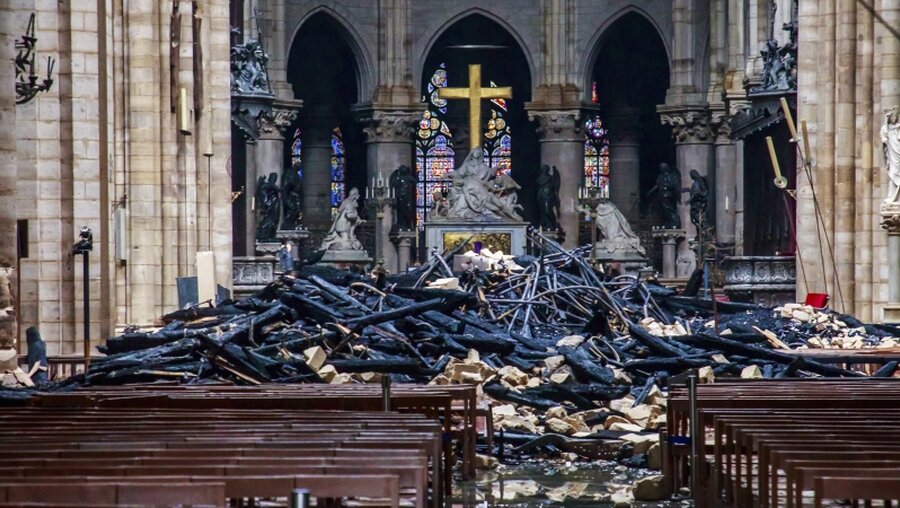 Trümmerteile und verkohlte Holzbalken liegen im Inneren der Kathedrale Notre-Dame / © Christophe Petit Tesson (dpa)