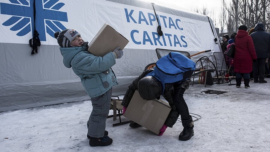 Kinder packen am 01.02.2017 in Awdijiwka in der Ostukraine Kartons auf einen Schlitten, die sie in einem Hilfszentrum bekommen haben. / © Evgeniy Maloletka (dpa)