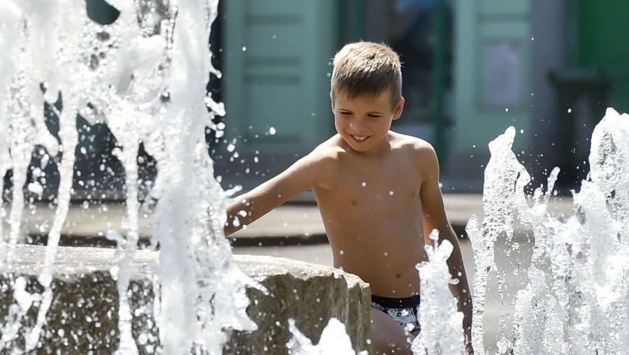 Urlaub in der Stadt: Ein Junge kühlt sich in einem Brunnen ab / © Vít Šimánek (dpa)