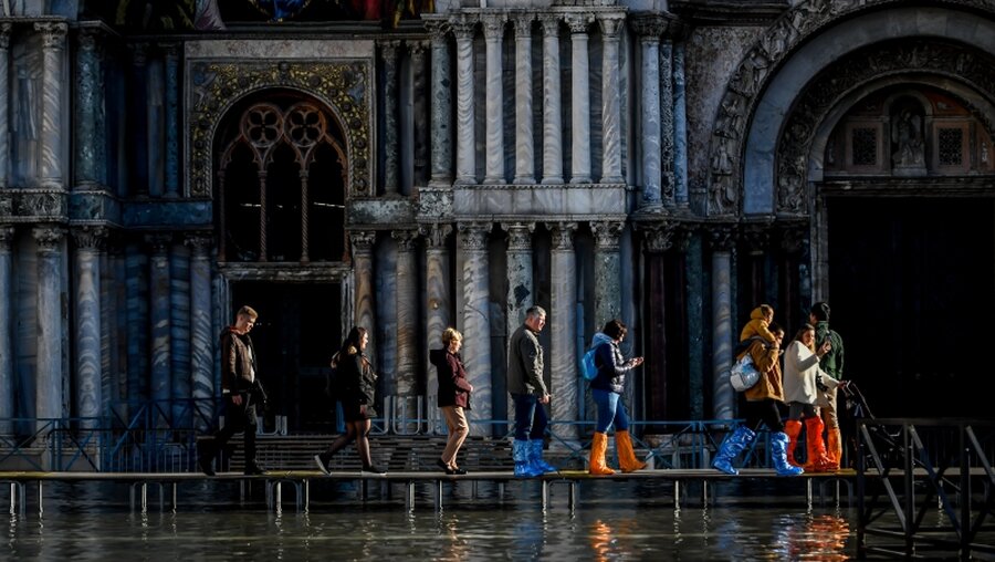 Venedig: Touristen gehen vor dem Markusdom über Stege / © Claudio Furlan (dpa)
