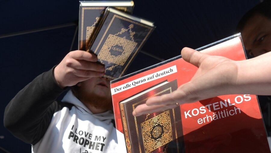 Ein Mann verteilt in der Innenstadt von Hannover kostenlose Koran-Exemplare an Passanten / © Julian Stratenschulte (dpa)