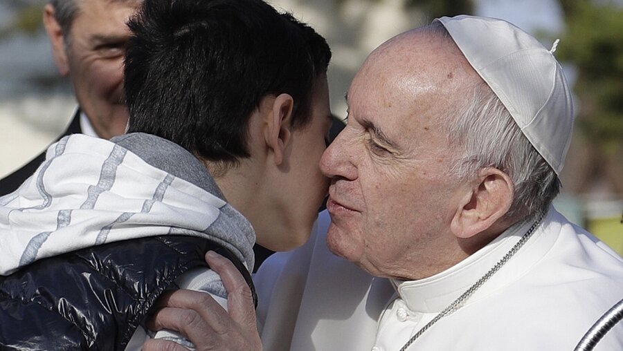 Papst Franziskus küsst in Rom einen Jungen.  / © Gregorio Borgia (dpa)