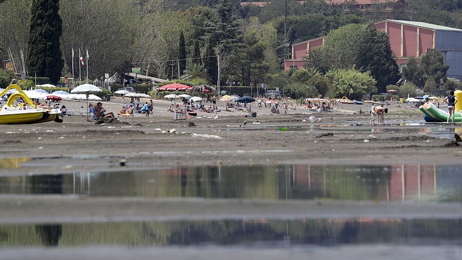 Menschen liegen am Ufer des Lago Bracciano, nördwestlich von Rom / © Andrew Medichini (dpa)