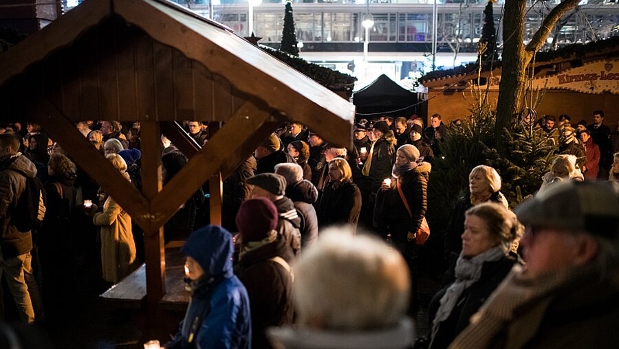 Zahlreiche Menschen stehen auf dem Weihnachtsmarkt am Breitscheidplatz in Berlin um den Opfern des Anschlags vor einem Jahr zu gedenken / ©  Bernd von Jutrczenka (dpa)