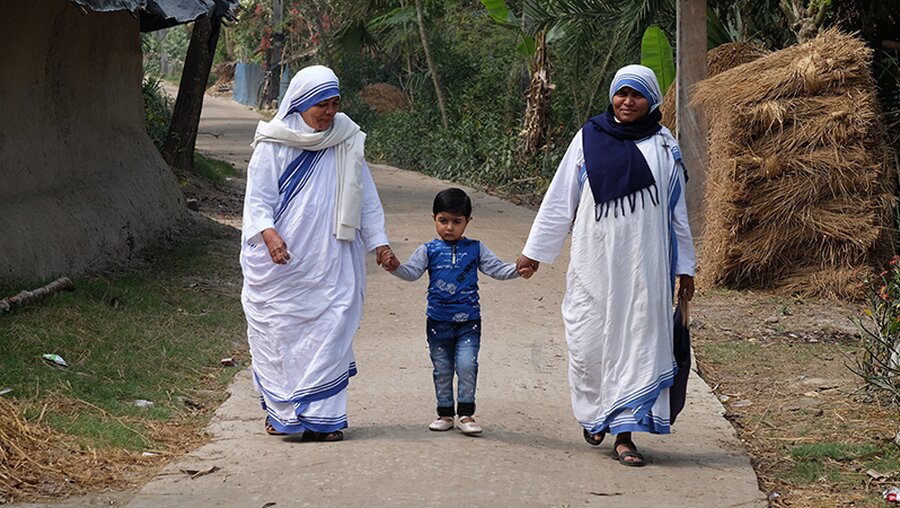 Zwei Schwestern des Ordens "Missionarinnen der Nächstenliebe" gehen mit einem Kind spazieren. / © Zvonimir Atletic (shutterstock)