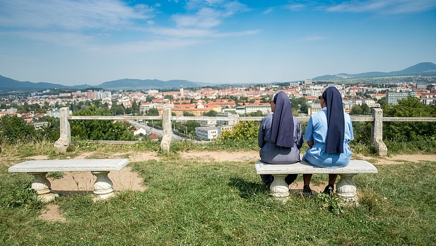 Zwei Schwestern sitzen auf einer Bank / © TOM KAROLA (shutterstock)