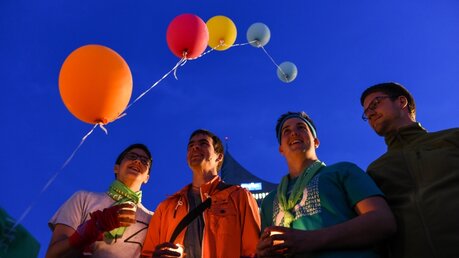 "Light of Christ", ein Stationenweg zu Fronleichnam im Rahmen des 100. Katholikentags in Leipzig am 26. Mai 2016 auf dem Augustusplatz.  Bild: vier jugendliche Teilnehmer halten eine Kerze, Luftballons steigen in den Himmel. (KNA)