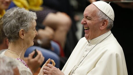 Papst Franziskus lacht während er eine ältere Frau aus Lyon begrüßt, bei einer Audienz im Vatikan am 6. Juli 2016. (KNA)