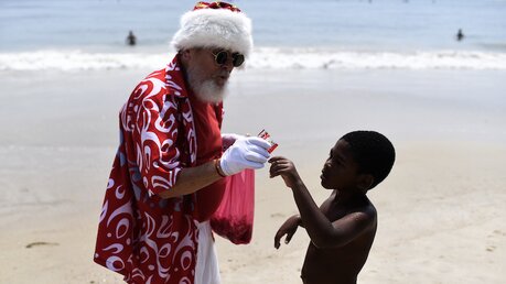 Der "Tropen-Nikolaus" verteilt Süßigkeiten am Strand von Copacabana (Brasilien) / © Fabio Teixeira (dpa)