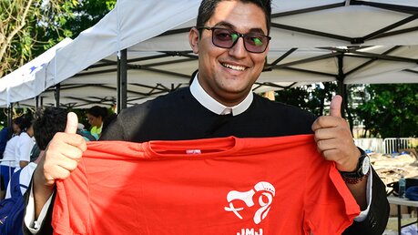 Ein Priester hält ein T-Shirt mit dem Logo des WJT / © Gennari/Siciliani (KNA)