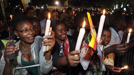 Gläubige halten Kerzen in Uganda  / ©  Daniel Dal Zennaro (dpa)